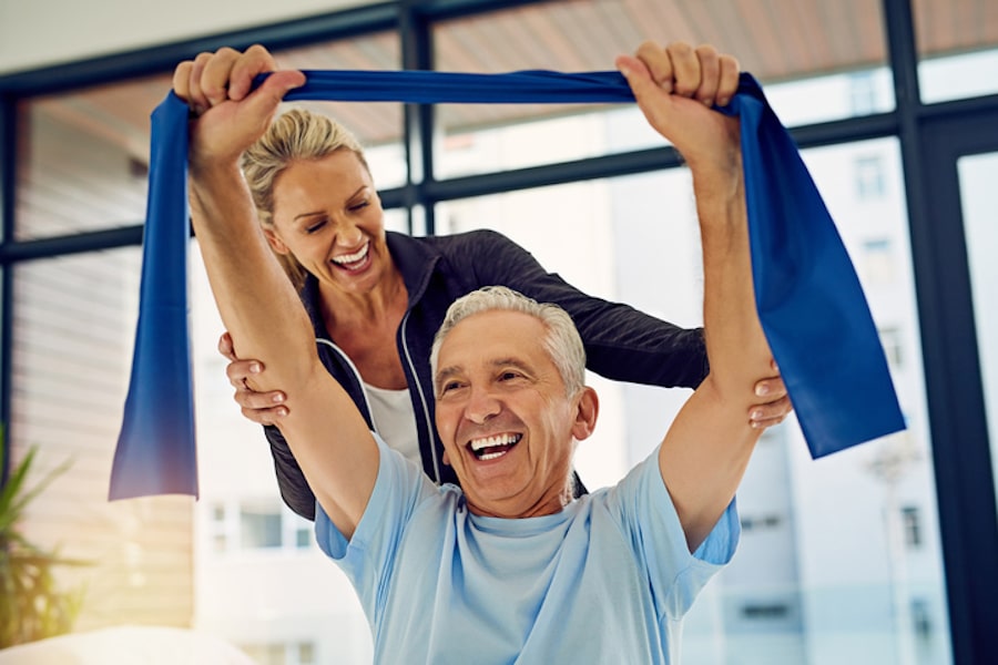 Physical therapist helping a senior patient stretch with a stretch band in her office