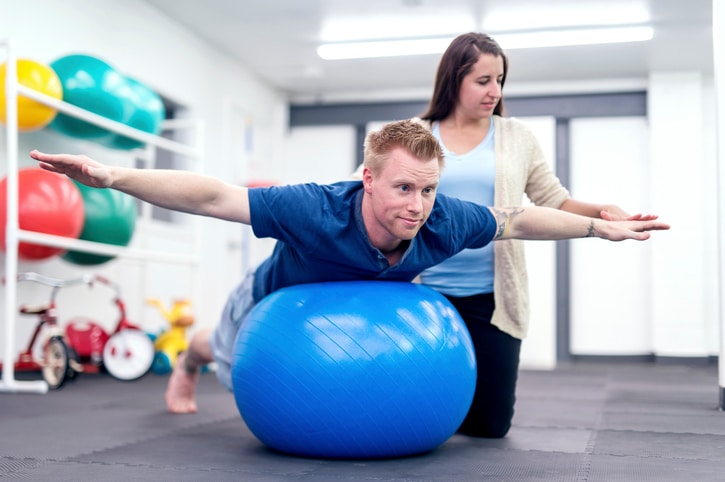 Adult male patient balancing on a therapy exercise ball