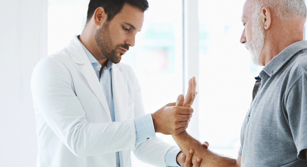 A man having his wrist examined by a doctor.